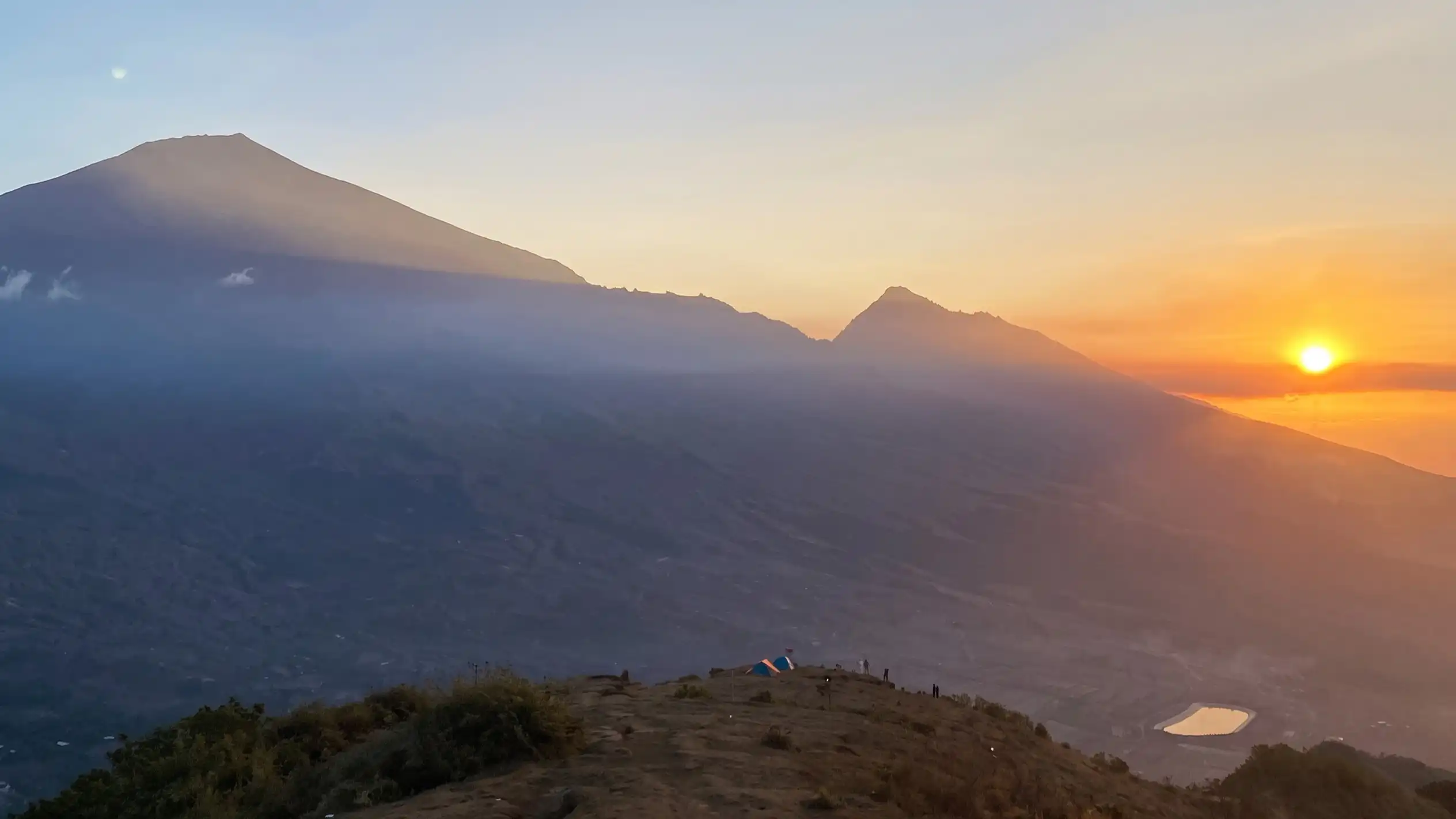 Tents on the ridge of Pergasingan Hill with sunrise over the Lombok mountains