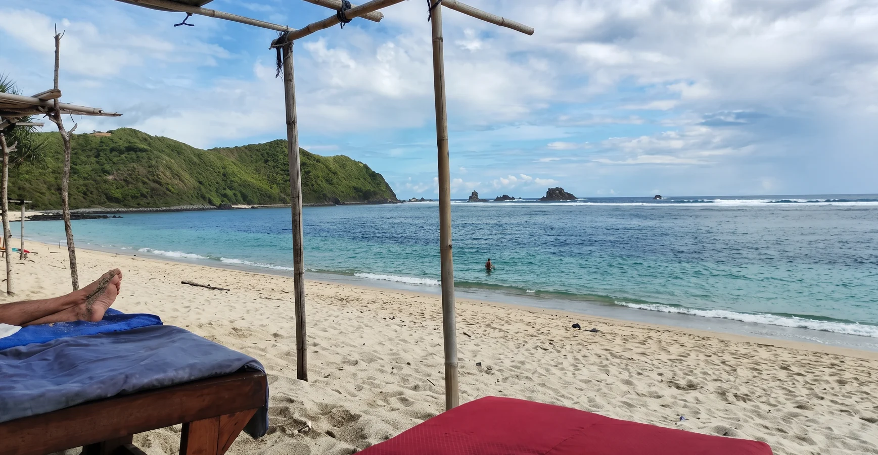Daybed under a simple beach shelter beside the turquoise bay at Tampah Beach
